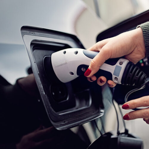 Woman is plugging/unplugging cable to electric car