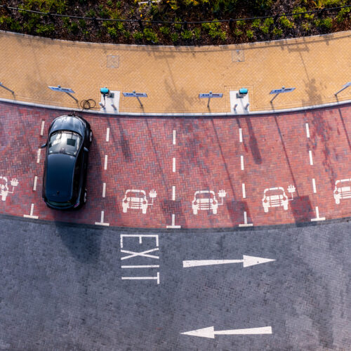 An aerial view directly above an electric vehicle charging station with electric car charging in a parking space