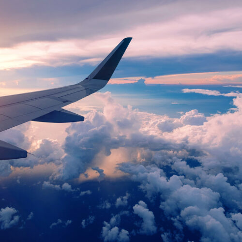 plane wingtip in flight over clouds